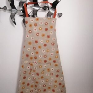 Tablier fleuri avec poche centrale. Fond beige et doublure orange