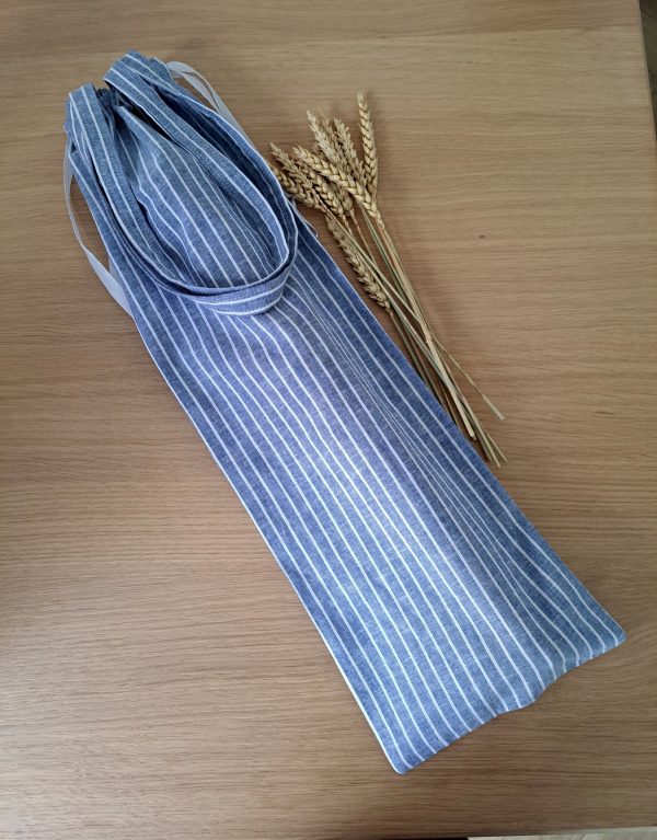 sac à pain posé sur une surface en bois clair à côté de quelques épis de blé.