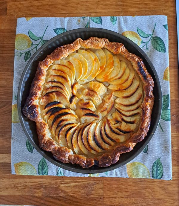 Sac à tarte “Petit Citron” posé sous une tarte aux pommes dorées, fond bois clair