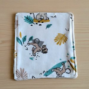 Lot de lingettes lavables artisanales avec motif lionceaux, disposées sur une table en bois pour le change de bébé.