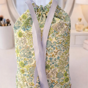 Pochon de rangement en coton bio fleuri contenant l'ensemble du kit Rituel Bien-Être Flânerie Florale : bandeau, lingettes, filet et savon.