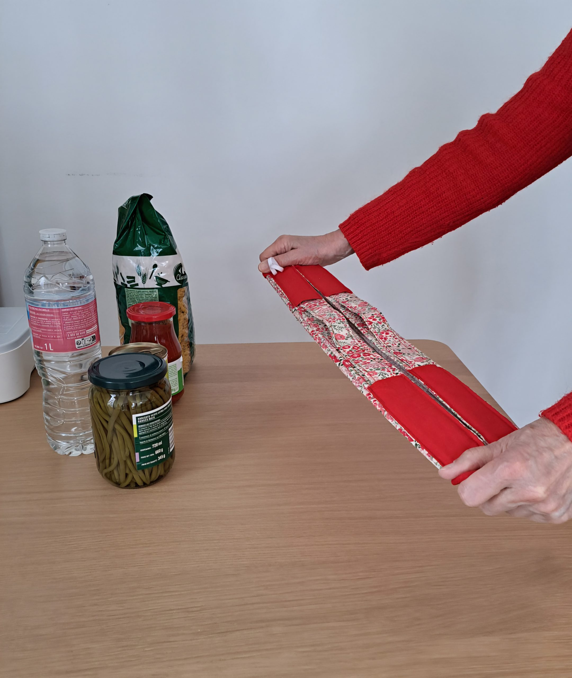 Démonstration du pliage compact du sac Pli Vite Capucine en coton à motifs rouges, système de fermeture rapide par tirage