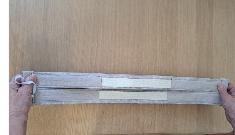 Démonstration du pliage d'un sac en coton Pli-Vite Fleuri : le sac est étiré par les extrémités pour se replier instantanément en accordéon