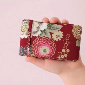 Sac Miette Kirei en tissu coton japonisant rouge fleuri, tenu dans la main d’un enfant – création artisanale Les Coutures de Miette