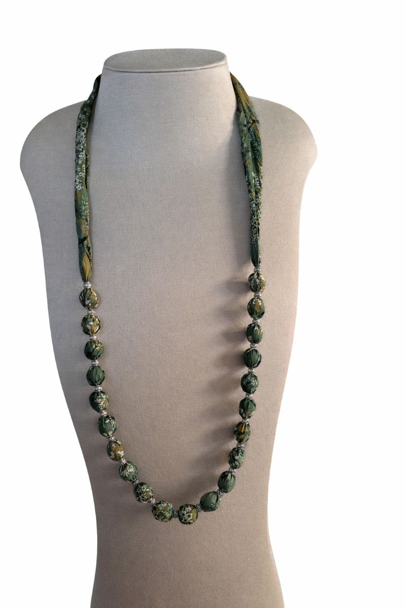 Collier sautoir bohème confectionné de perles en bois brut recouvertes en tissu Liberty vert et de délicats intercalaires argentés.